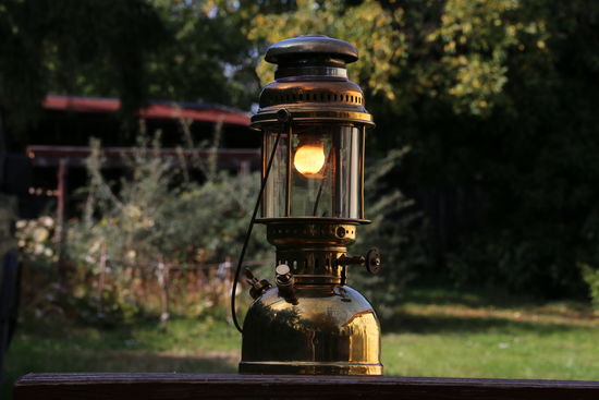 petrolejová lampa Optimus 300 – rozsvícená v zahradě za denního světla